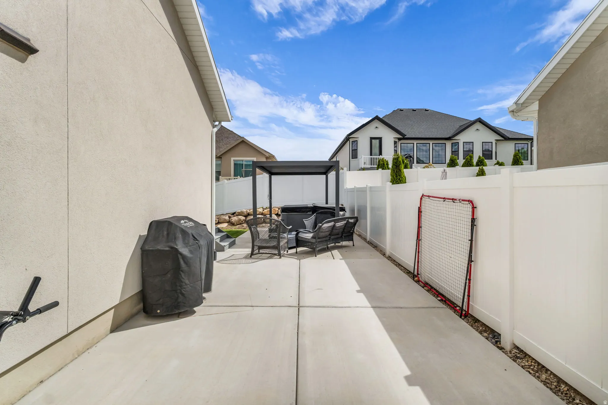 Outdoor patio with concrete hardscaping, a modern pergola, and a private perimeter fence