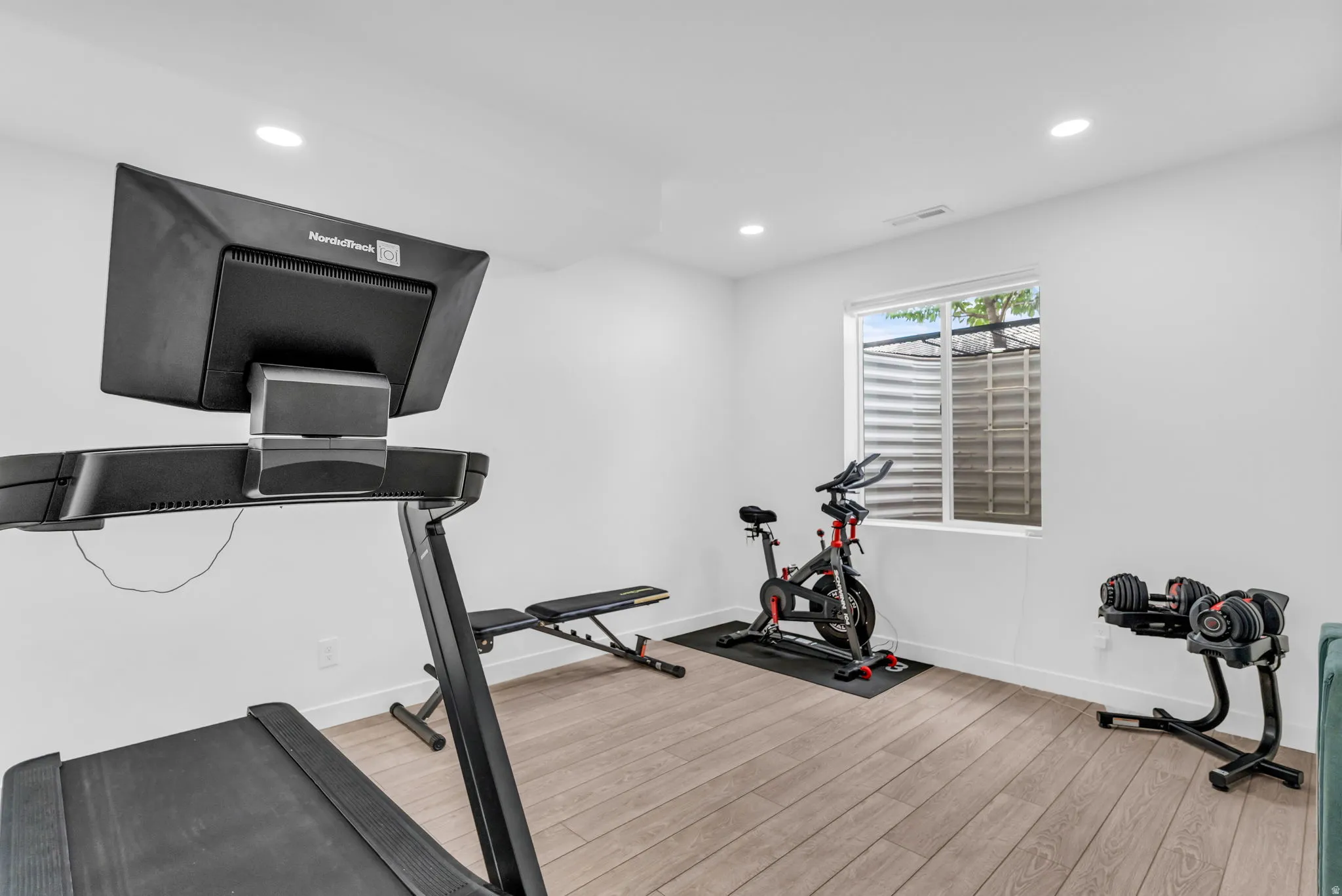 Bright room featuring light wood-finish flooring and recessed lighting