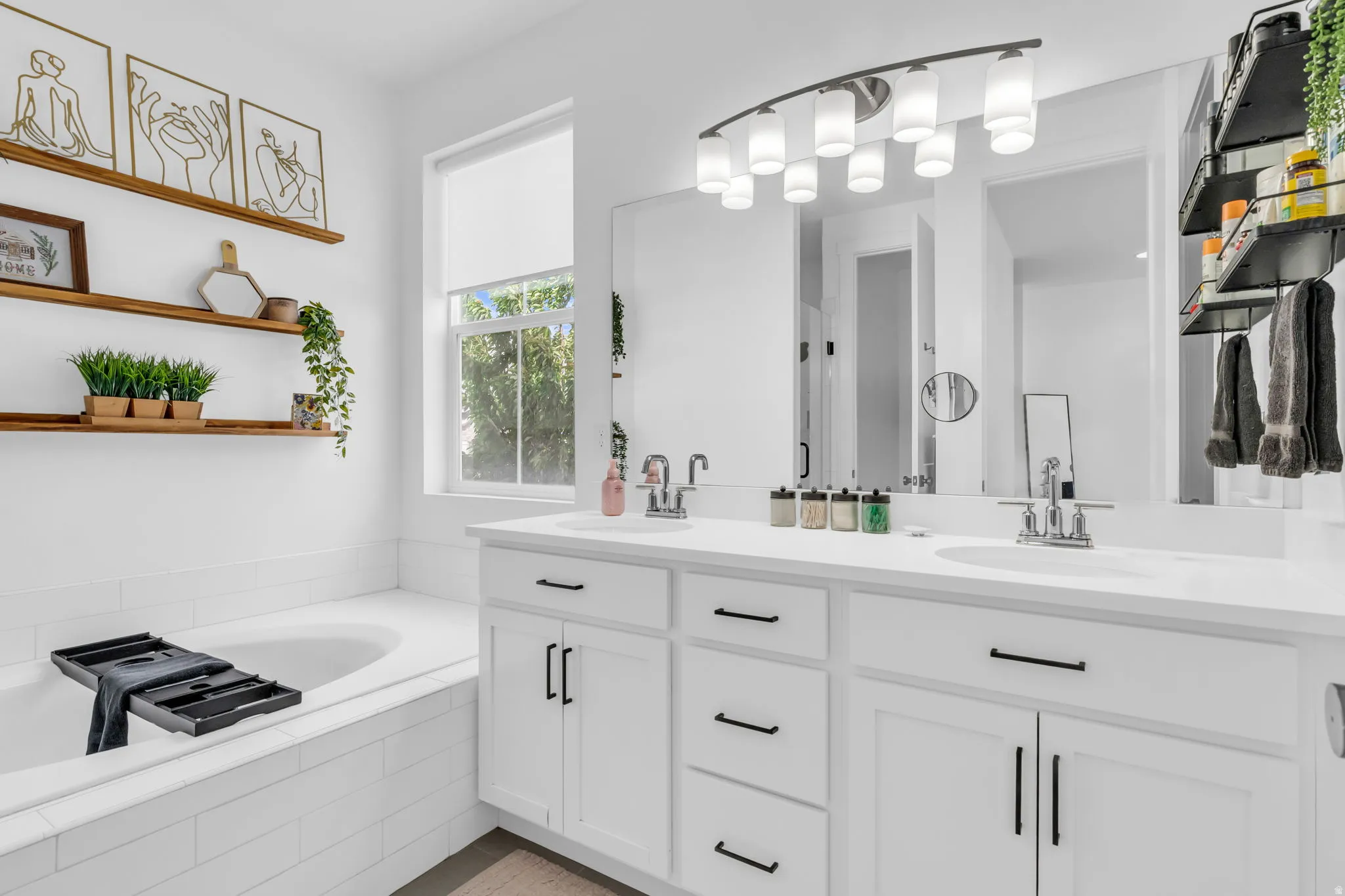 Dual vanity with white cabinetry and black hardware, featuring a double basin sink and a large framed mirror
