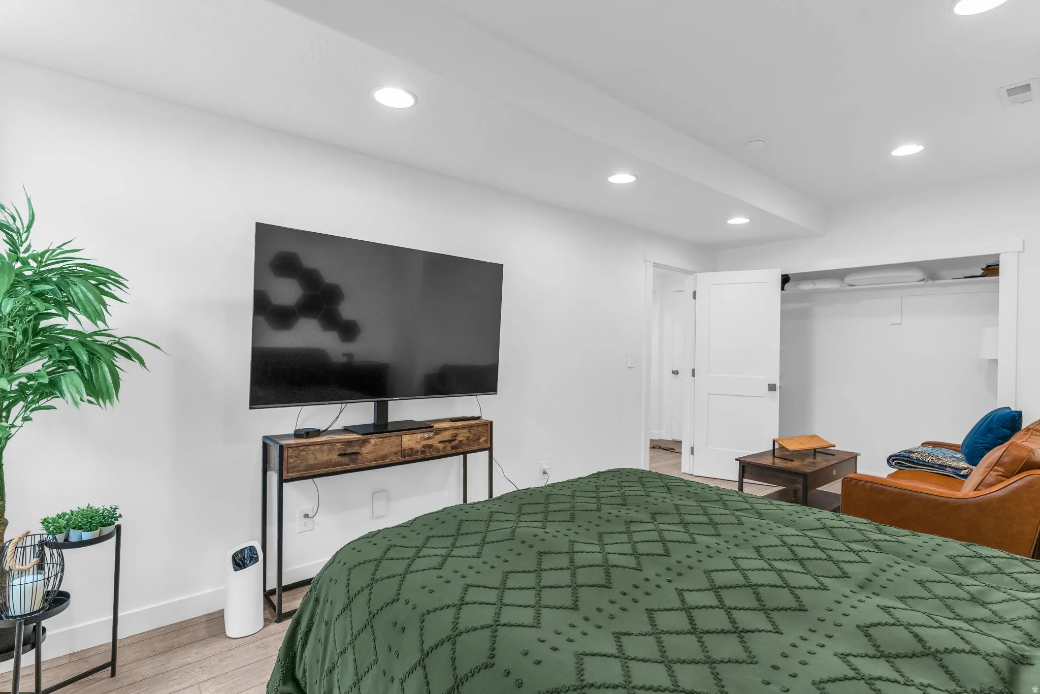 Recessed lighting illuminates a spacious room featuring light wood-finish flooring