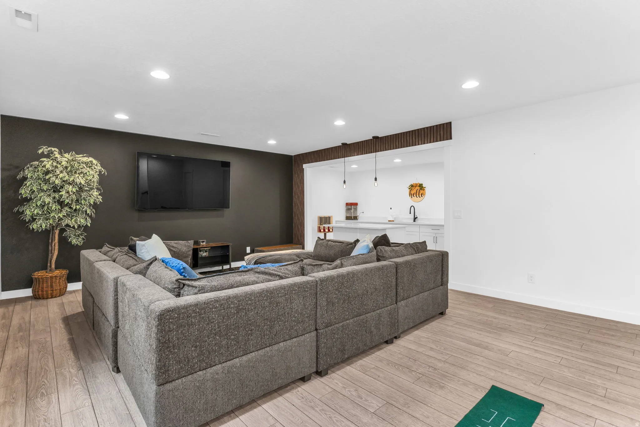 Entertainment area featuring wood-finish flooring, recessed lighting, and a dark accent wall