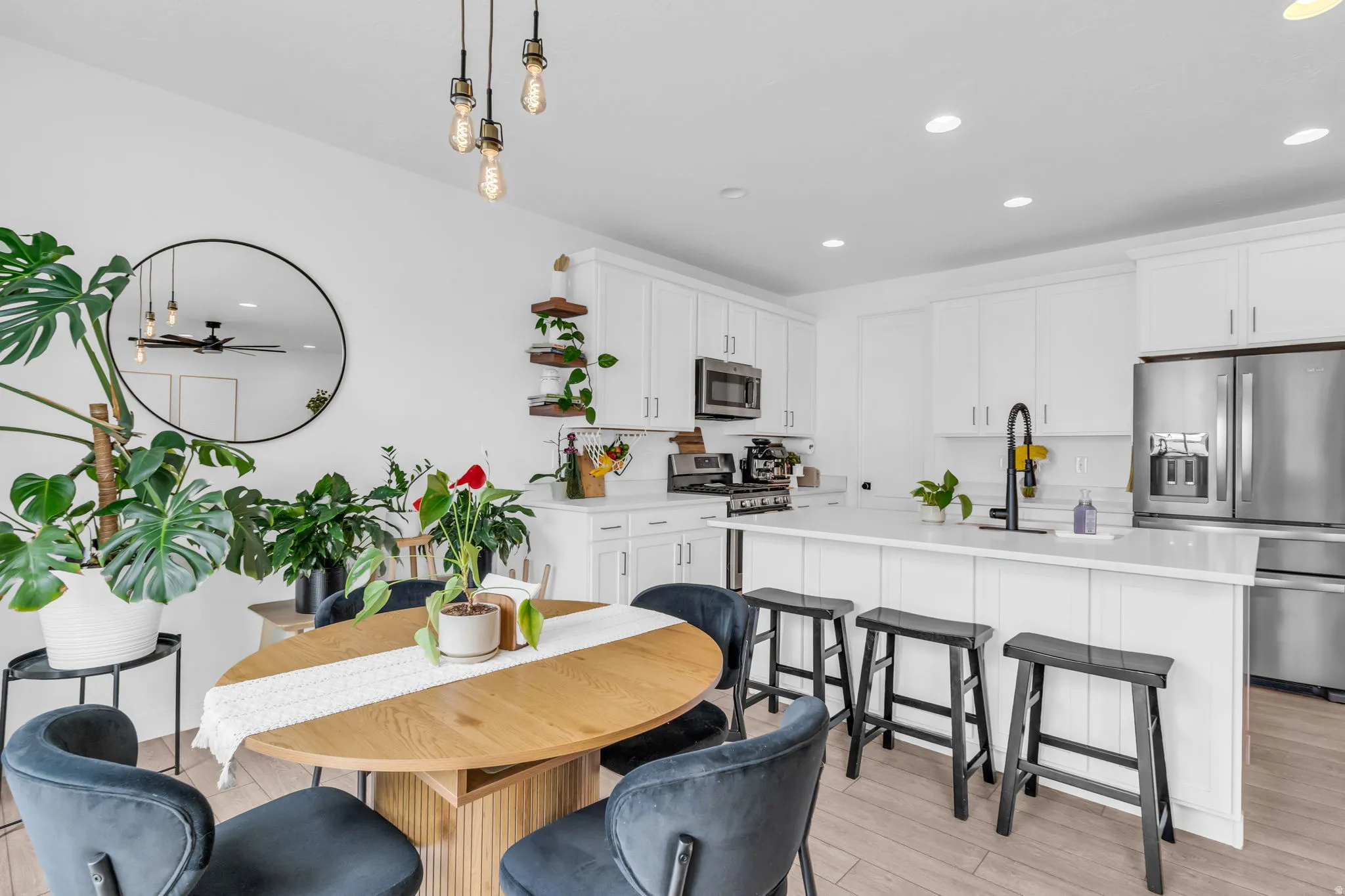 Open-concept kitchen and dining area featuring white cabinetry, stainless steel appliances, a center island with bar seating, and recessed lighting