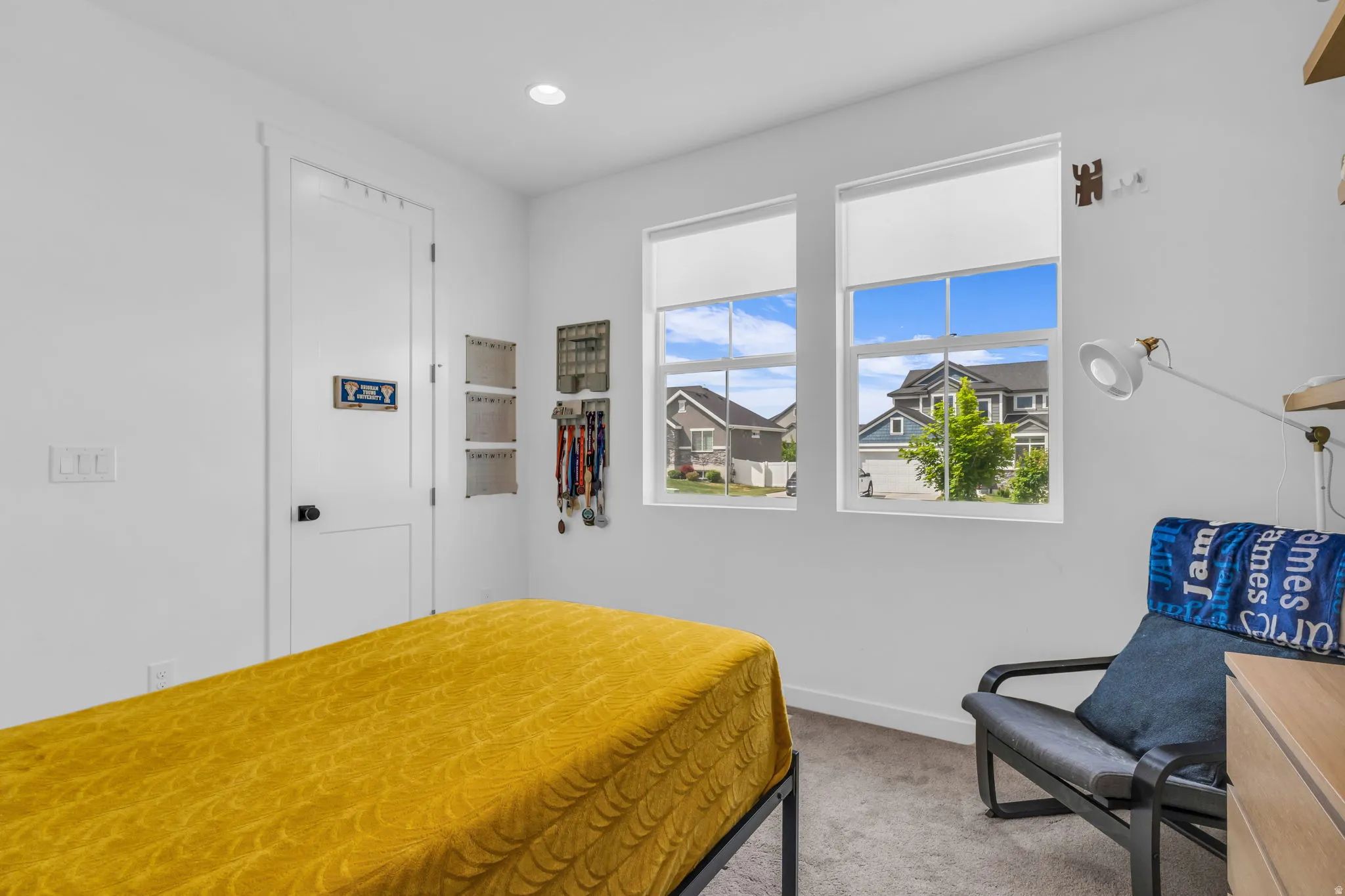 Interior room featuring light gray wall paint, two large windows, recessed ceiling lighting, and gray carpeting