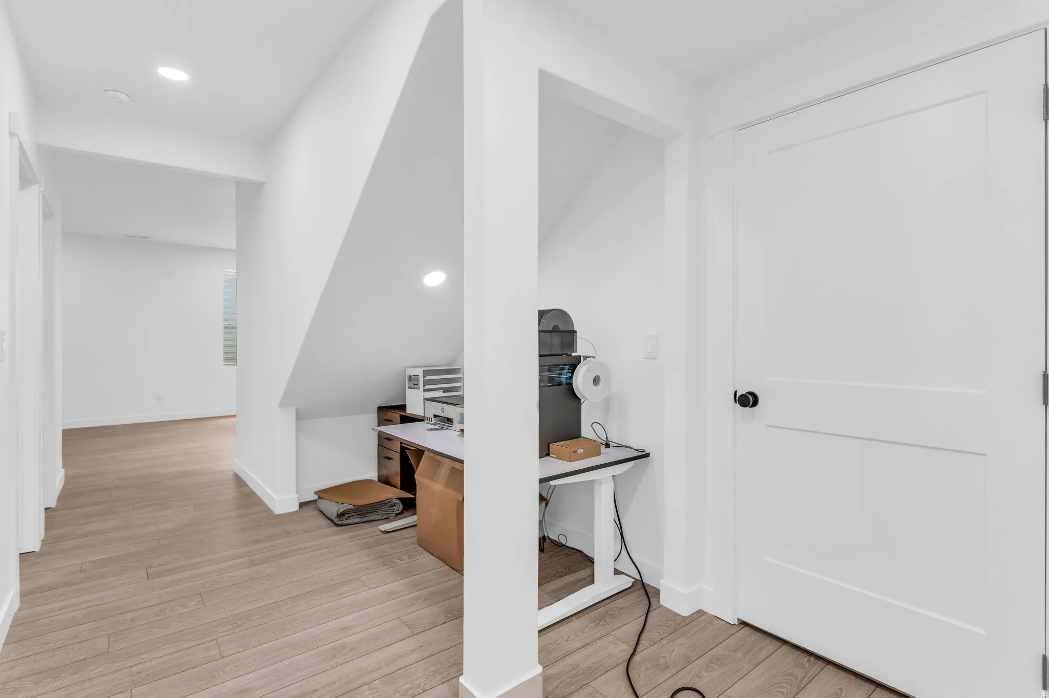 Hallway featuring wood-finish flooring, recessed lighting, and a built-in under-stair alcove