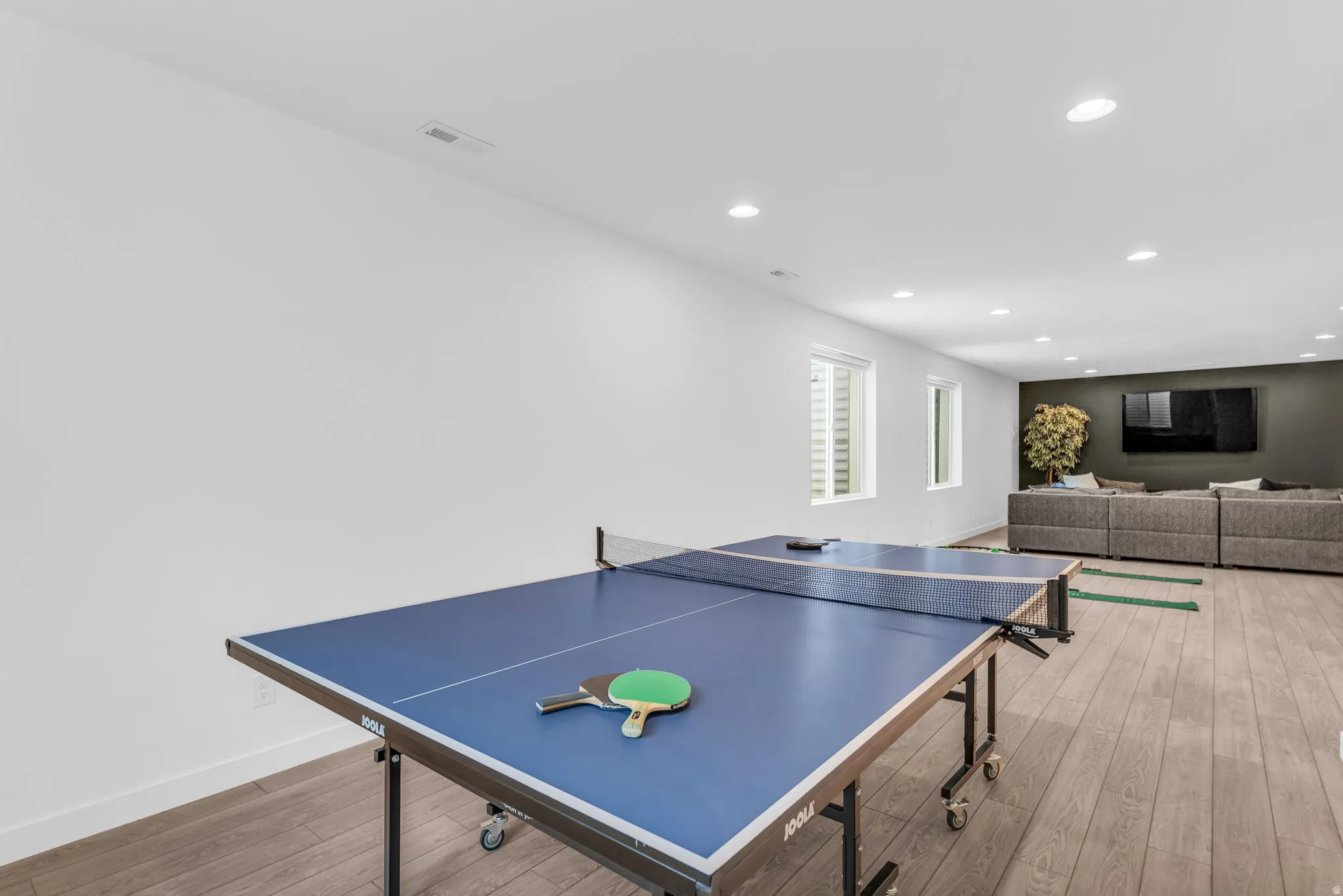 Finished basement area featuring recessed lighting, wood-finish flooring, and white walls