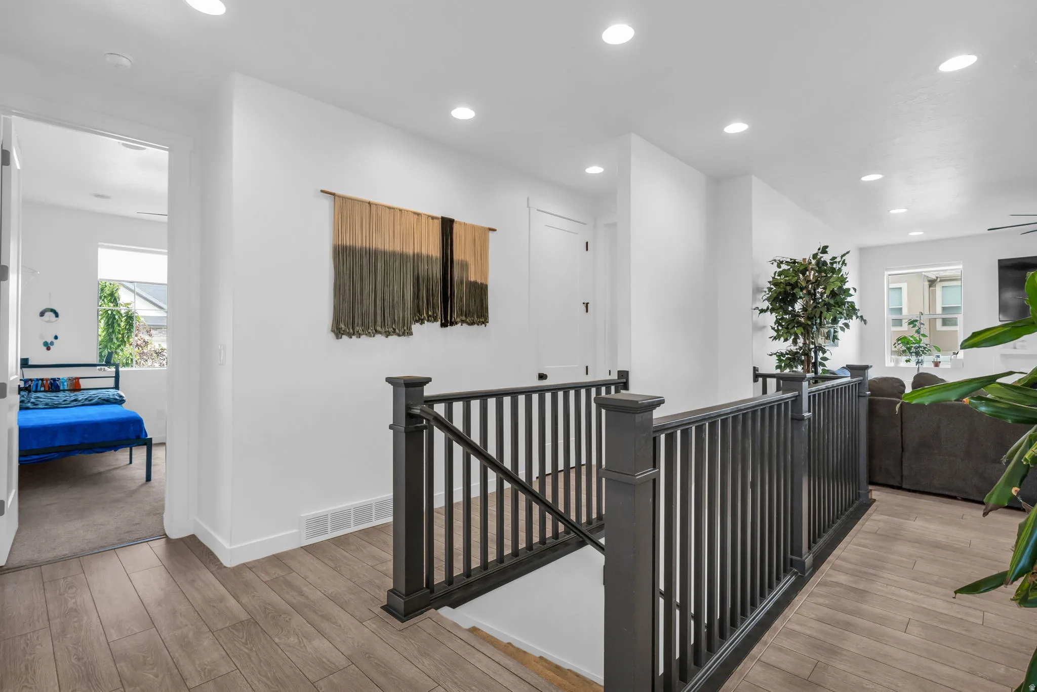 Upper-level landing featuring wood-finish flooring, recessed lighting, and dark-stained railing