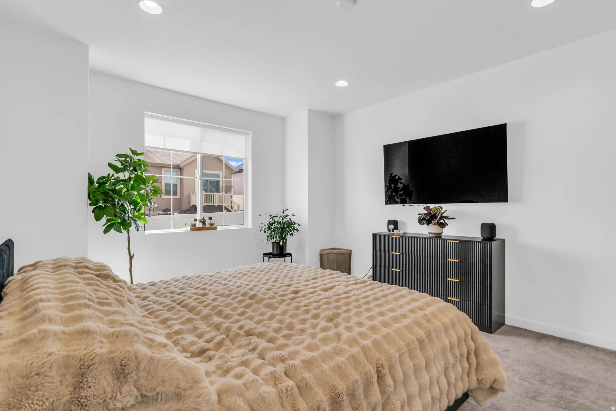 Bedroom featuring neutral-toned carpet, recessed lighting, and a large window with roller shades