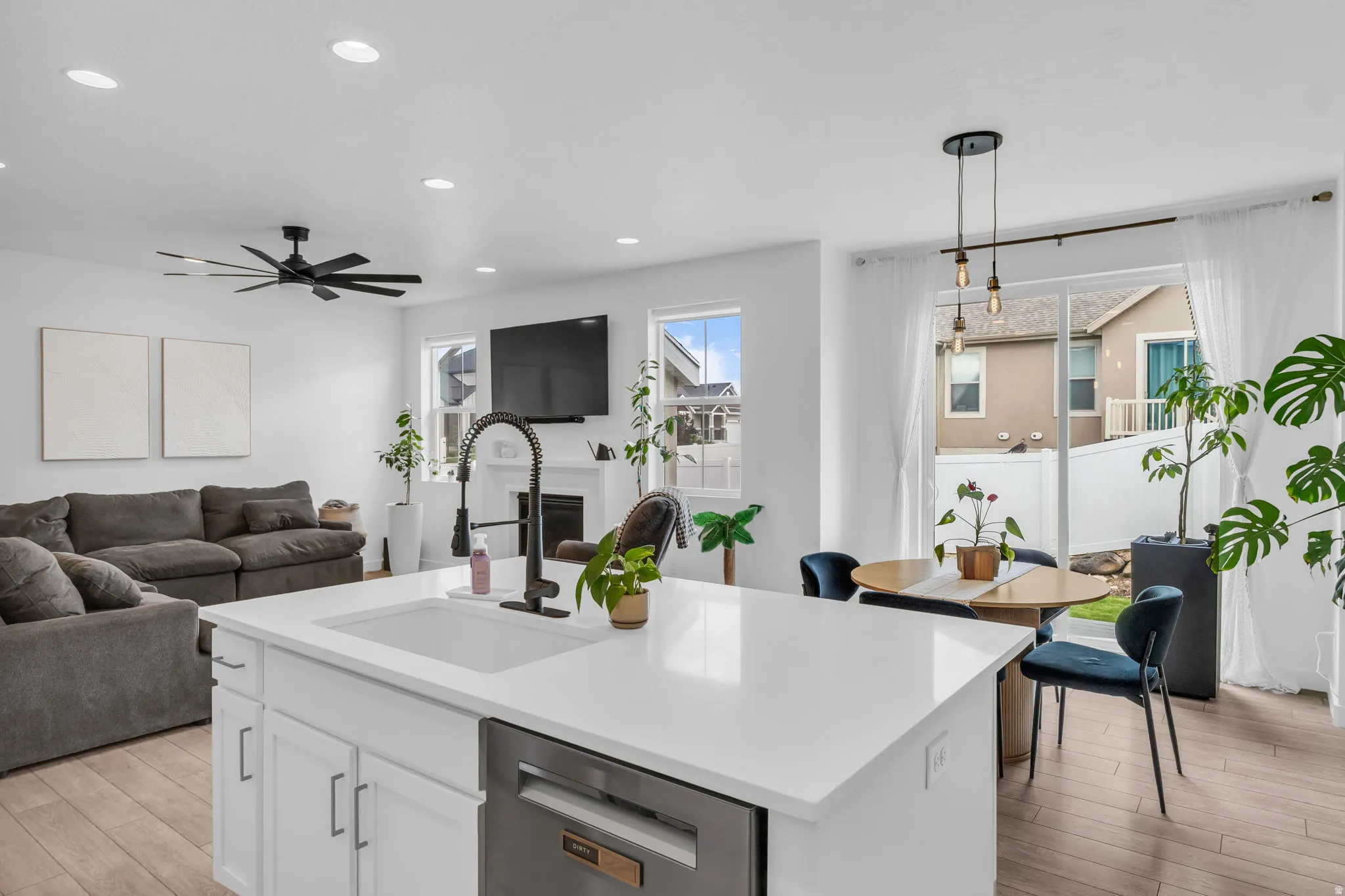 Central kitchen island with an integrated sink, white cabinetry, and a stainless steel dishwasher