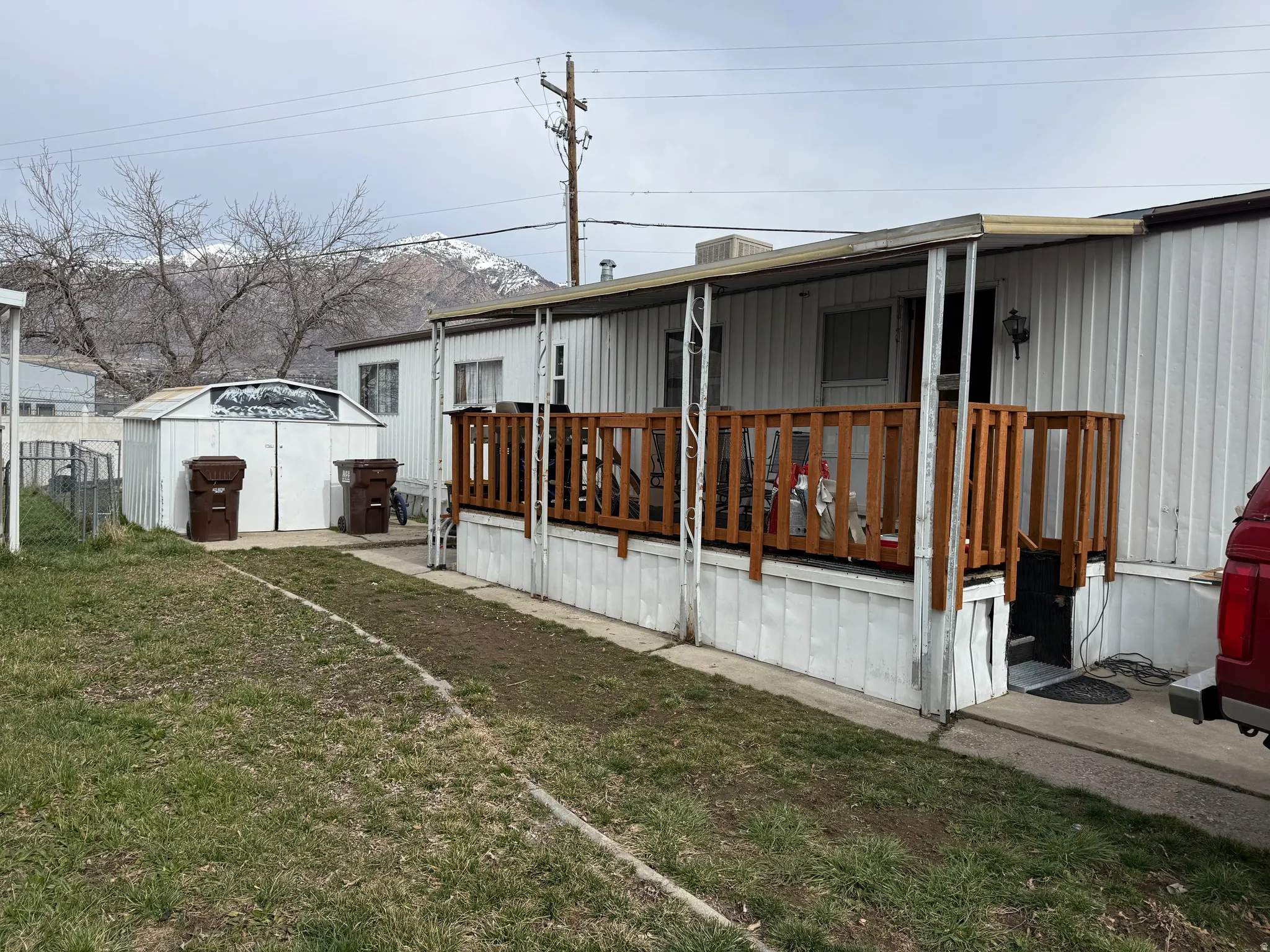 Exterior featuring a covered porch with wood railing, white siding, and an outdoor storage shed