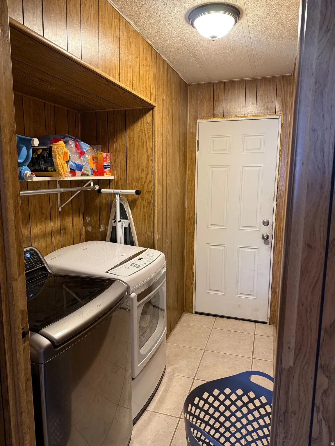 Laundry area featuring wood-finish wall paneling, a built-in shelf, and tile flooring