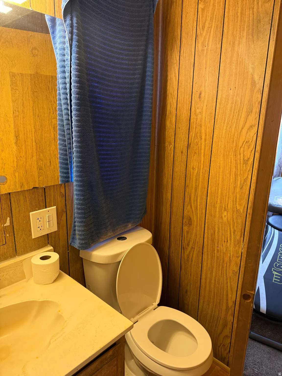 Bathroom featuring wood-finish paneling, an integrated sink vanity, and a white toilet