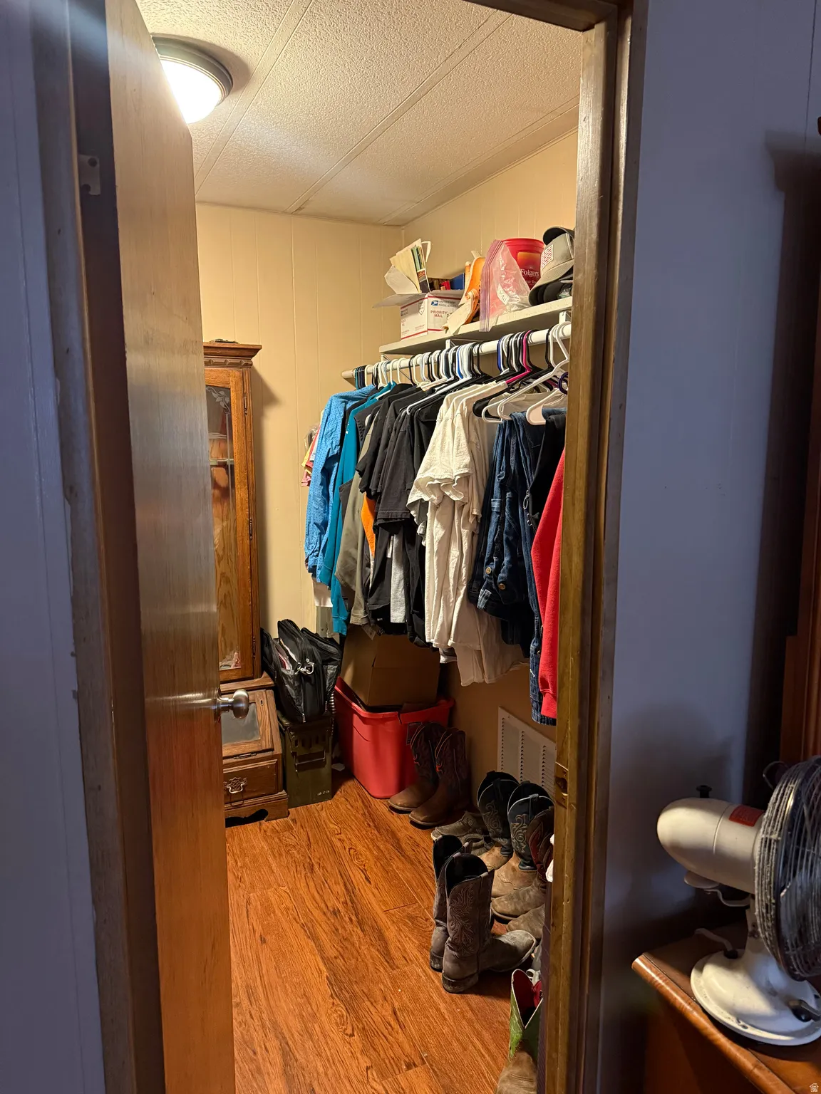 Walk-in closet featuring wood-finish flooring, built-in shelving, and hanging rod organization