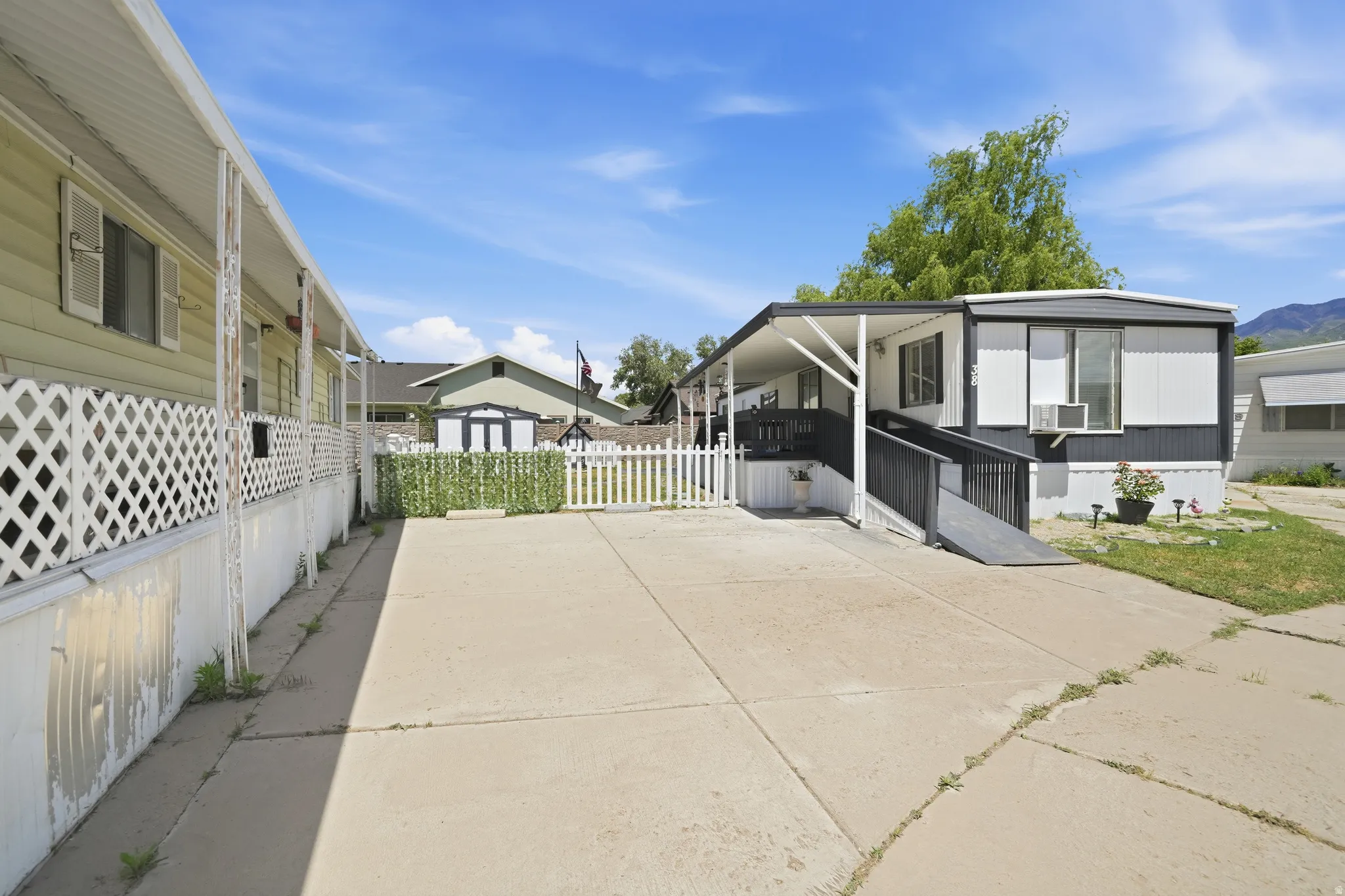 Mobile home featuring a dark gray and white exterior, covered porch, and an accessibility ramp