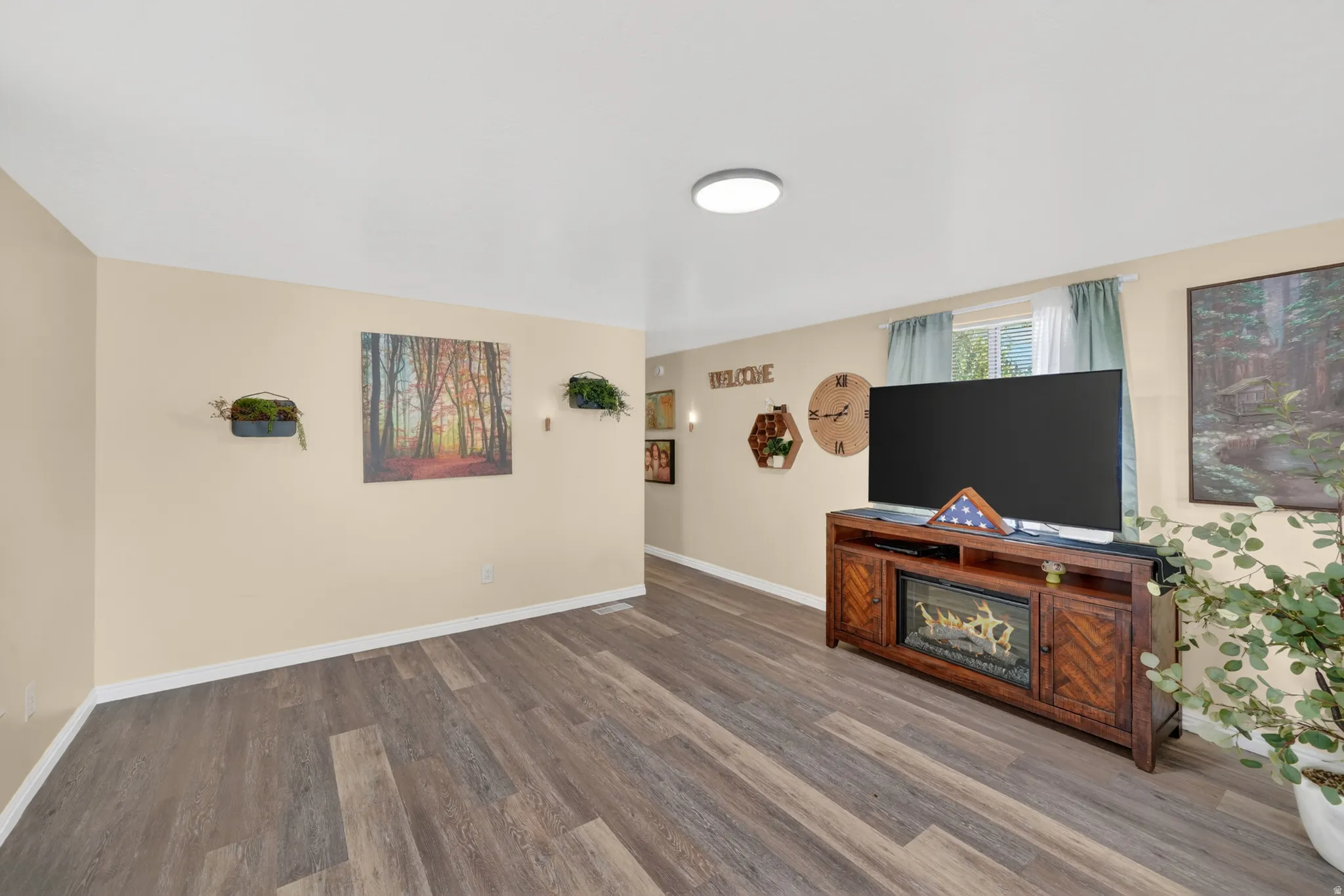 Spacious room featuring wood-finish flooring, light-toned walls, and a recessed ceiling light