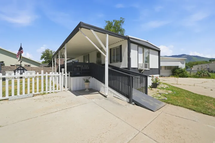 Manufactured home with covered porch, white picket fence, and a concrete driveway