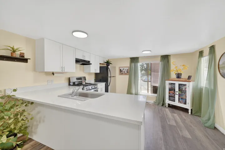 Kitchen featuring white cabinetry, light-colored countertops, stainless steel sink, and wood-finish flooring