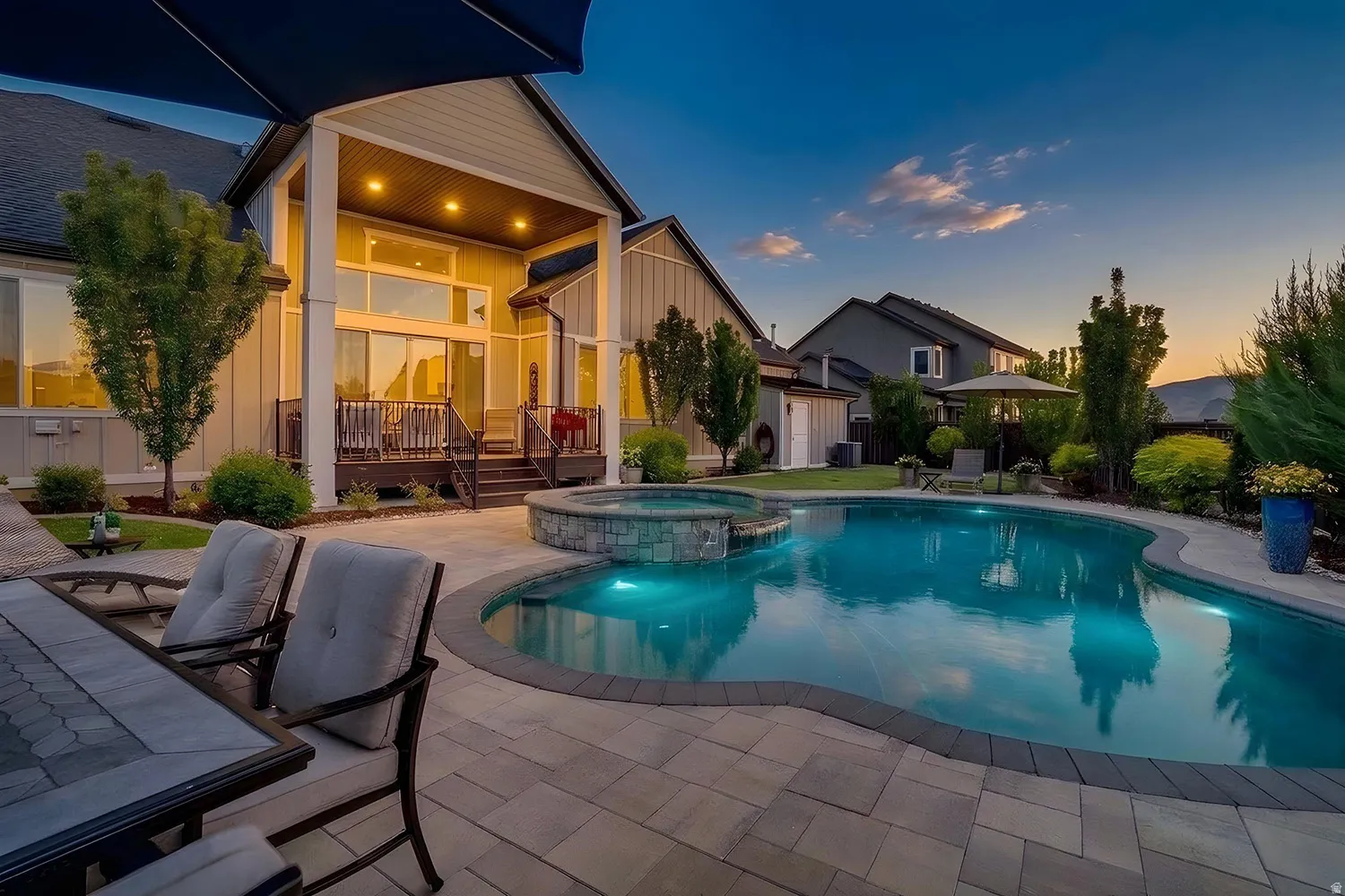 Outdoor living space featuring a freeform swimming pool, integrated spa with stone surround, and a spacious paver patio