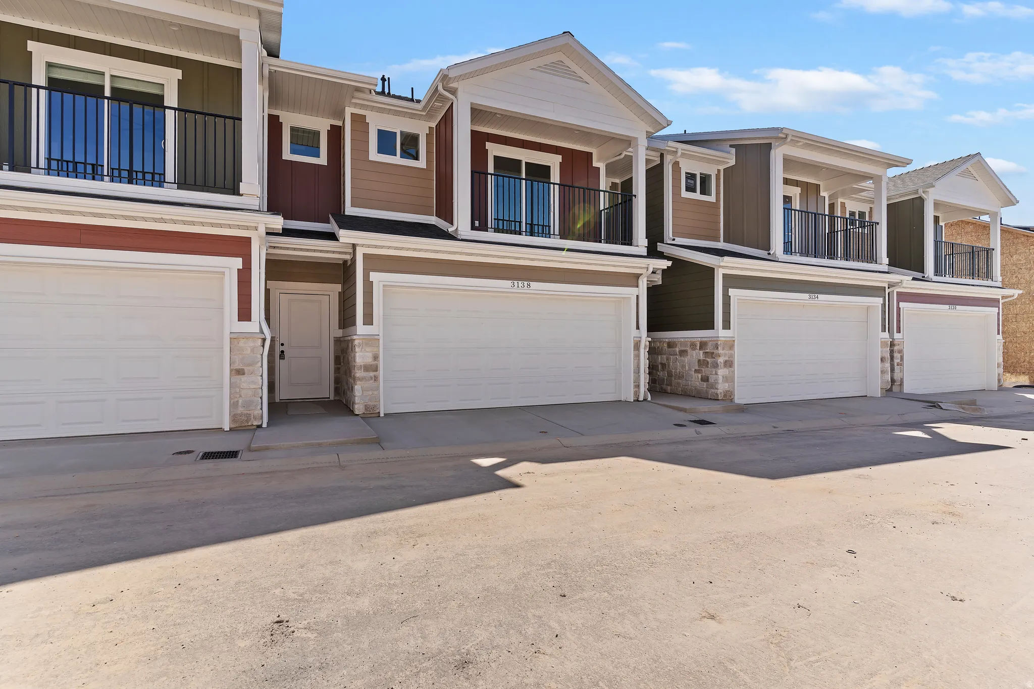 Contemporary townhome exterior featuring multi-toned siding, stone accents, and a covered balcony with black railings