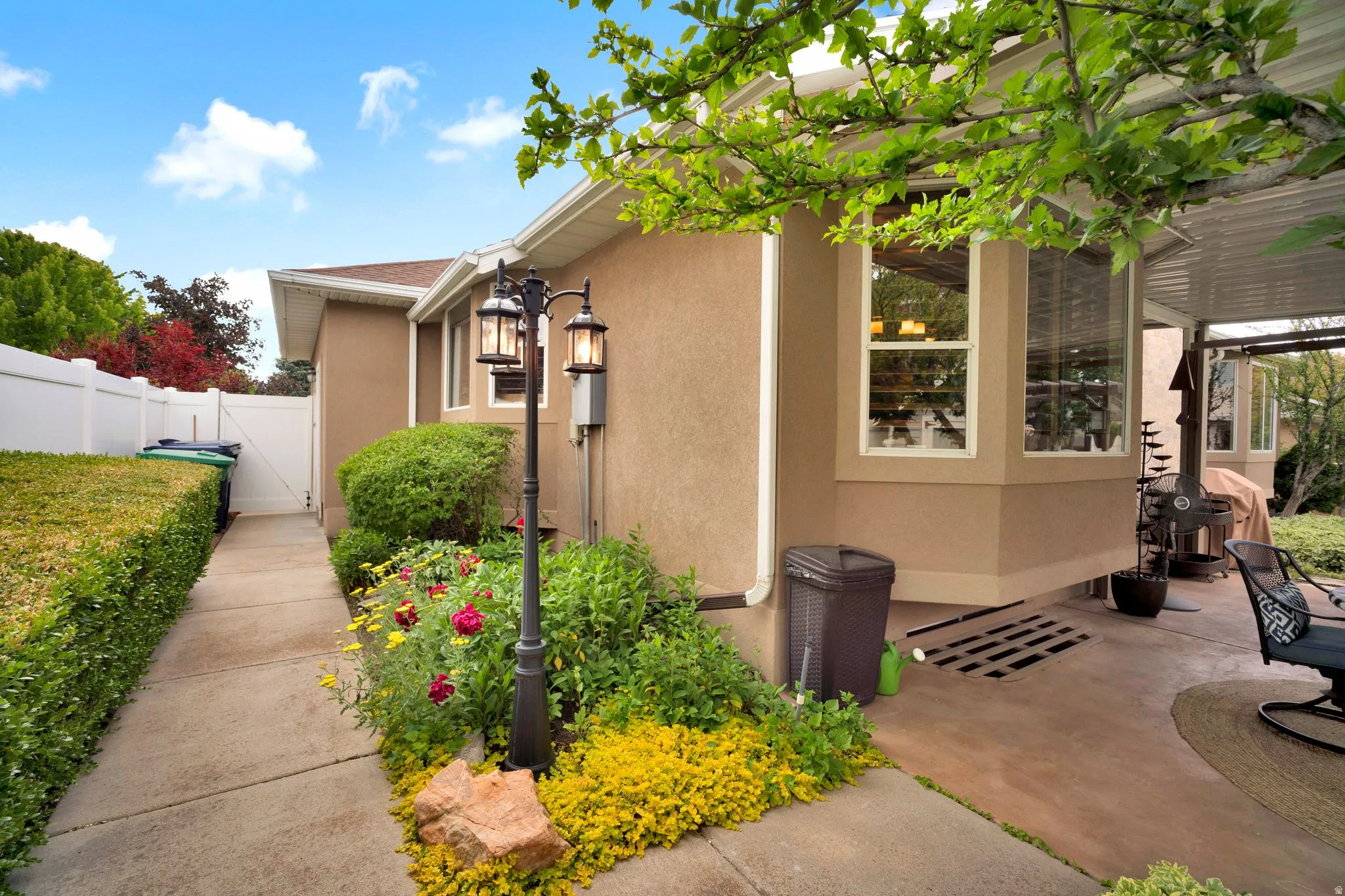 Backyard with outdoor lighting, stained concrete patio (covered) and walkway to front yard.