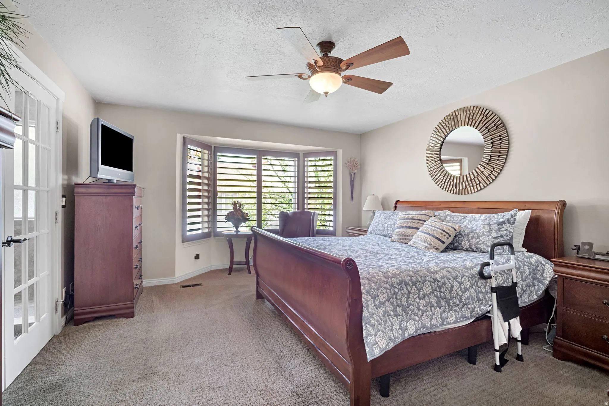 Primary bedroom with bay window and wood plantation shutters.  French doors to primary bathroom.