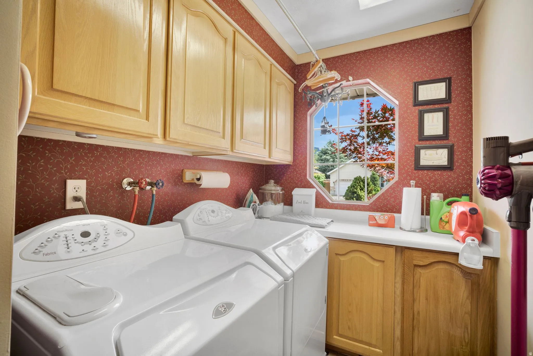Dedicated laundry room featuring a geometric window looking out from front of the home.  Tons of cabinet storage.  Convenient hallway location.
