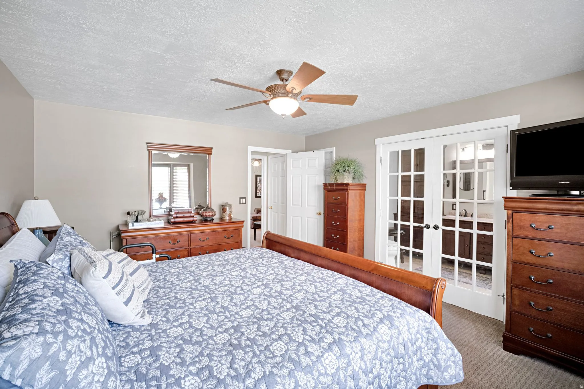 Primary bedroom with ceiling fan, french doors to primary bath, walk-in closet.