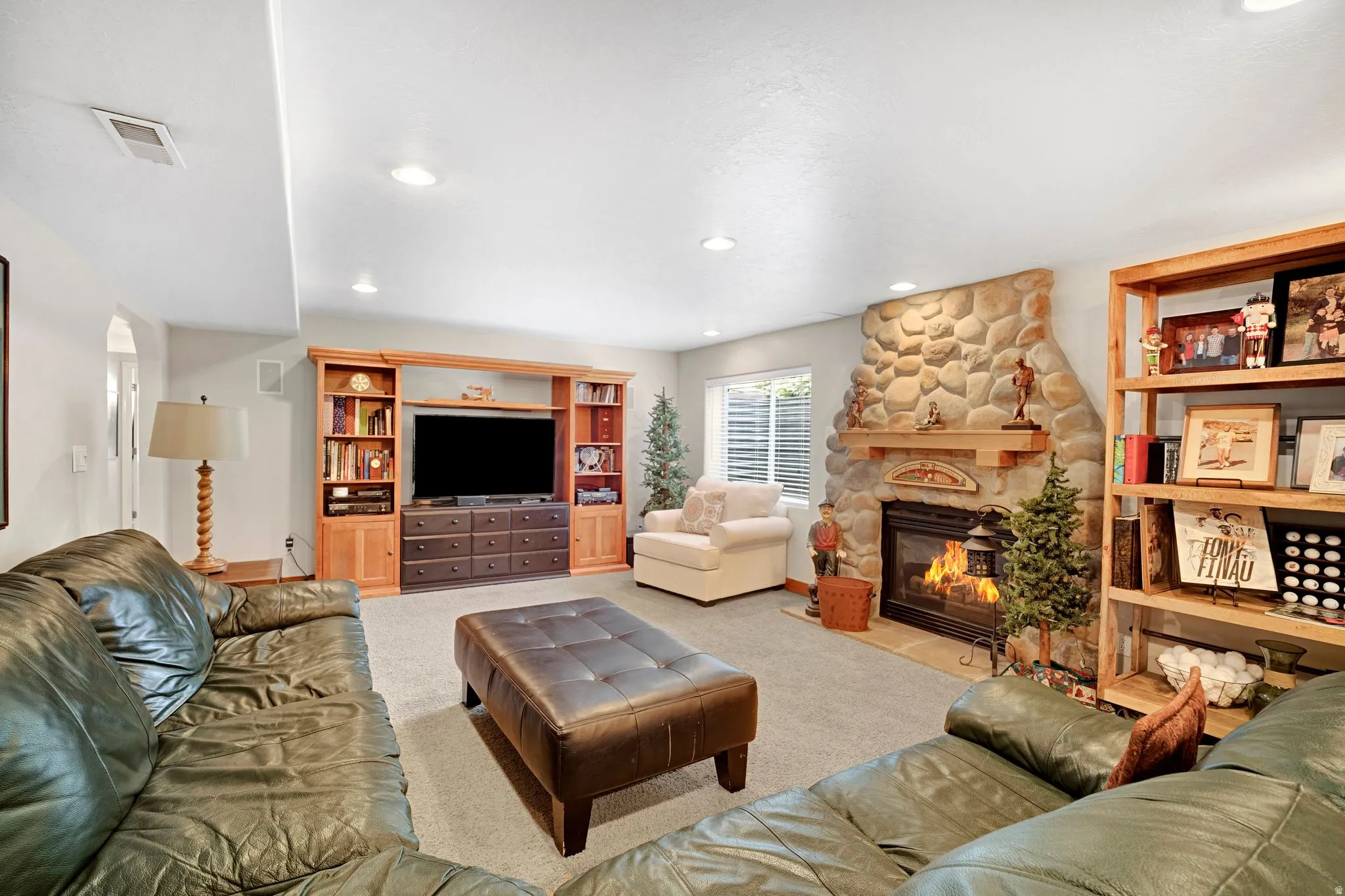 Spacious recreation room featuring a stone-clad heatilator fireplace with a welcoming mantle.