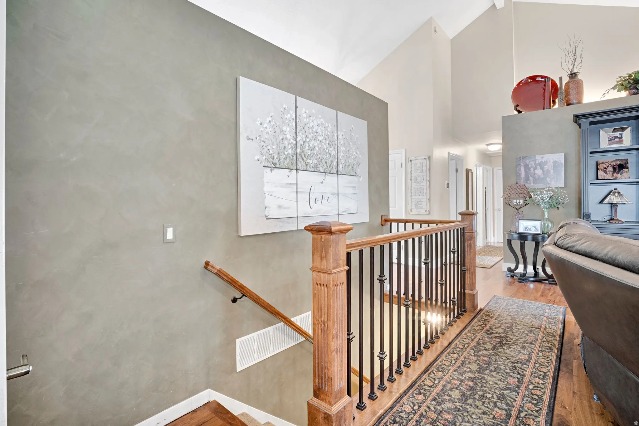 Staircase with updated wood handrail and black metal balusters.