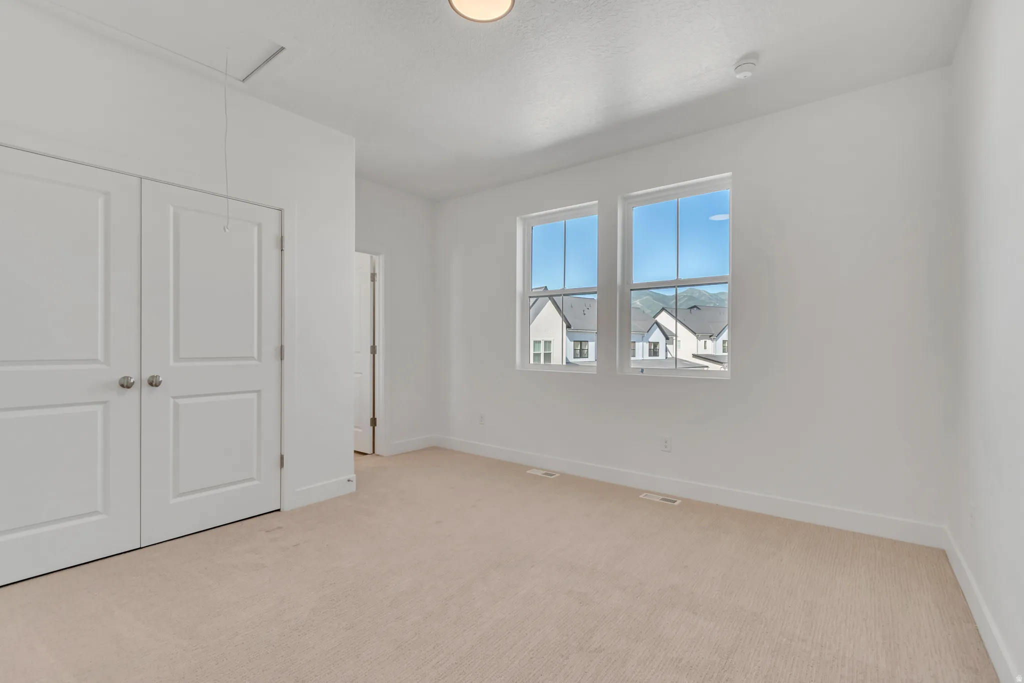 Bright interior featuring two large windows, white walls, and neutral carpeting