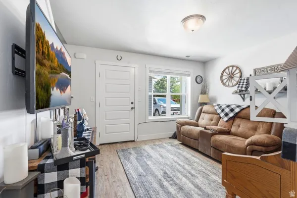 Living area featuring wood-finish flooring, a contemporary overhead light fixture, and a white paneled door