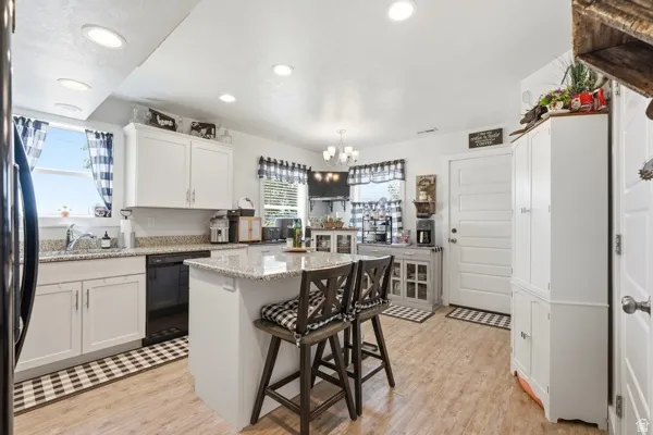 Kitchen featuring light wood-finish flooring, white cabinetry, recessed lighting, and a center island with a granite-style countertop
