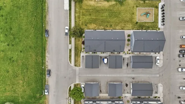 Aerial perspective highlighting multi-unit residential properties with dark shingle roofs, individual garages, and paved driveways