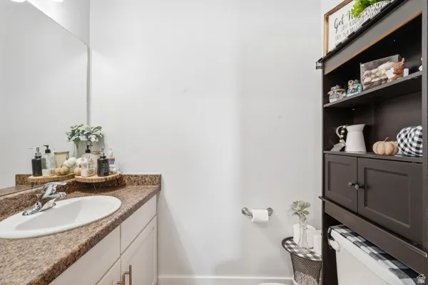 Bathroom featuring a single vanity with a laminate countertop, undermount sink, and a large wall-mounted mirror