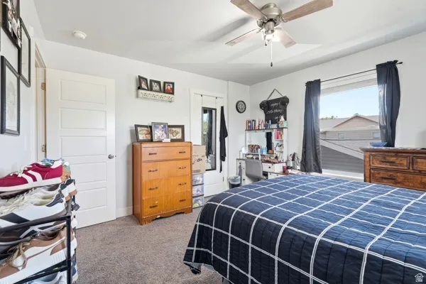 Carpeted room with a ceiling fan, white paneled door, and a window with dark drapes