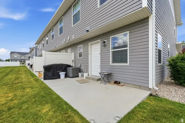 Concrete patio area with a white privacy fence and a manicured lawn