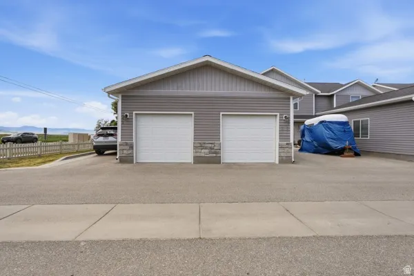 Two-car garage featuring white paneled doors and stone veneer accents