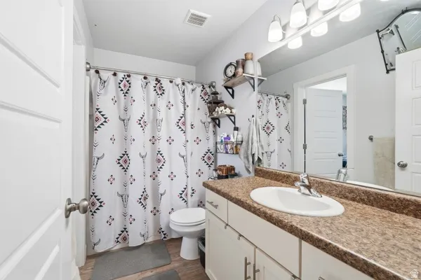 Full bathroom featuring a single vanity with an integrated sink, a large mirror, and overhead vanity lighting