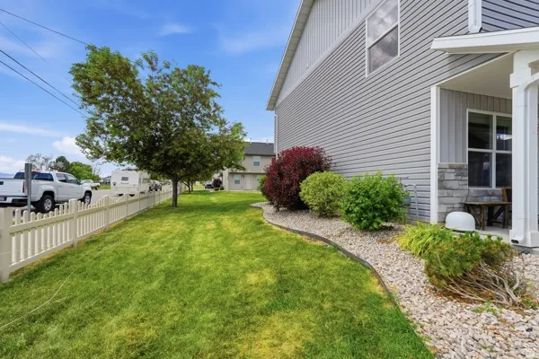 Exterior featuring grey siding with stone accents, a covered porch, and a white picket fence