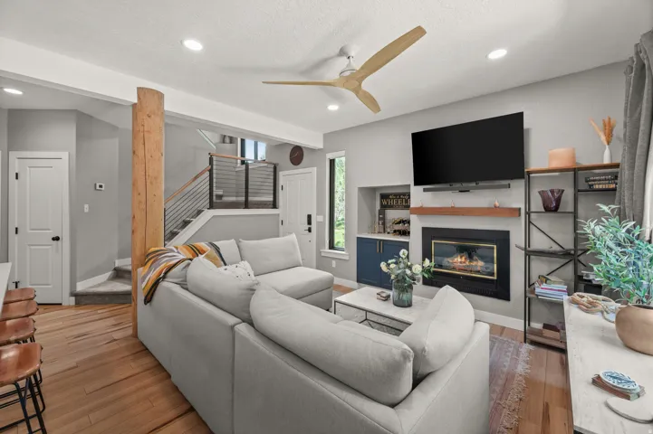 Open-concept living area featuring wood-finish flooring, a built-in fireplace with a hearth, and built-in cabinetry