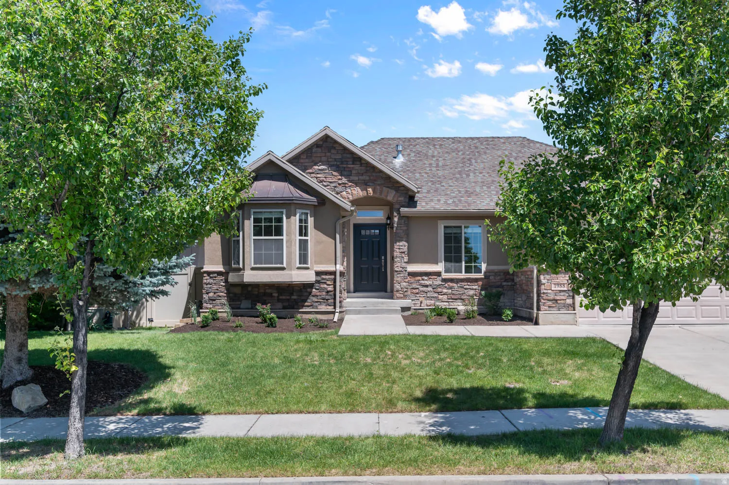 Stone and stucco facade home with a covered entry