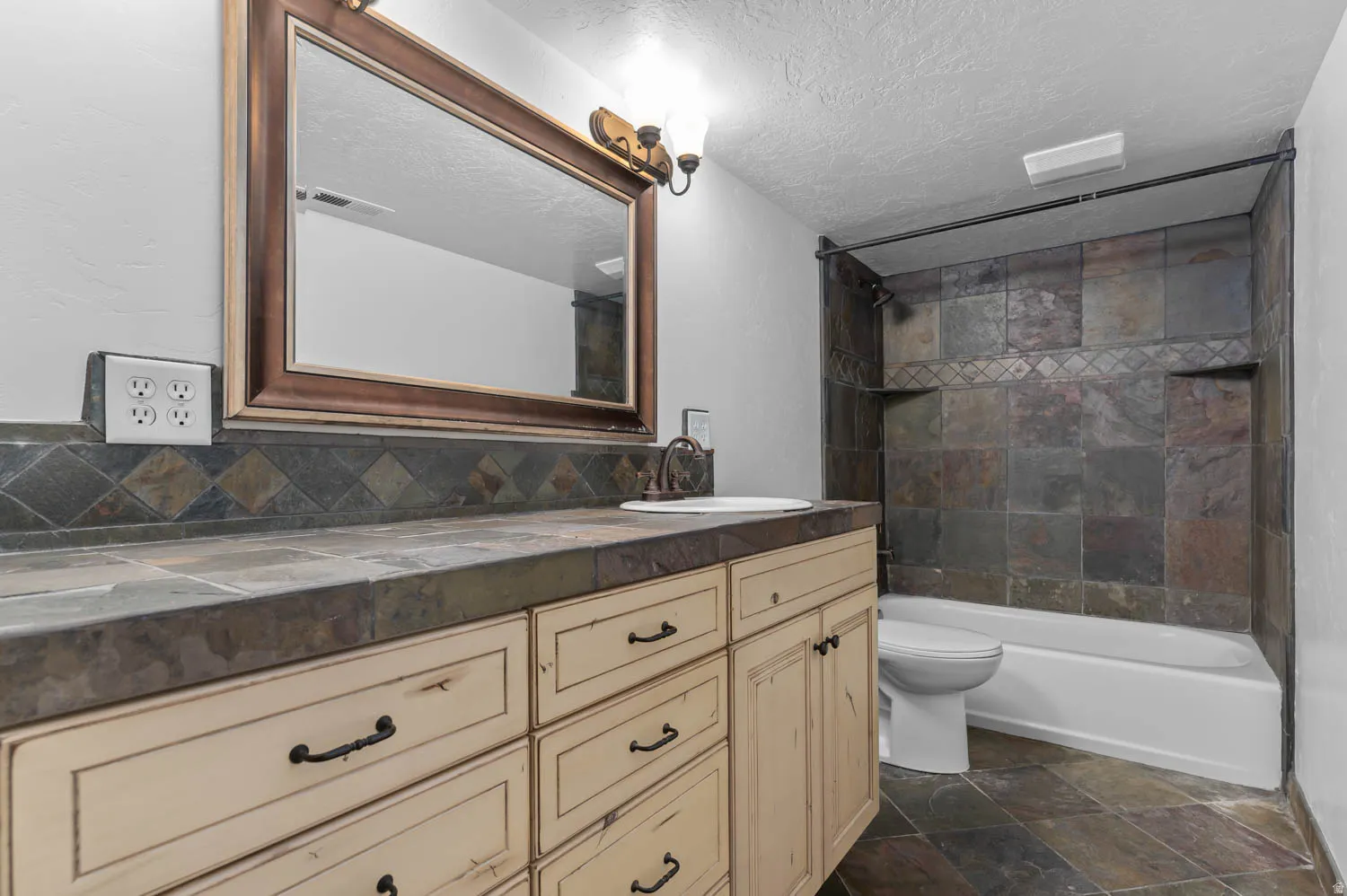 Bathroom featuring an integrated vanity with light-toned cabinetry, a dark-toned countertop, and a vessel sink
