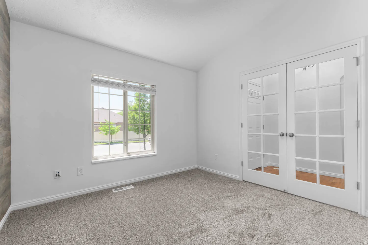 Room featuring vaulted ceilings, plush carpet, a window with horizontal blinds, and French doors with glass panes. Currently used as an office. Could be a bedroom