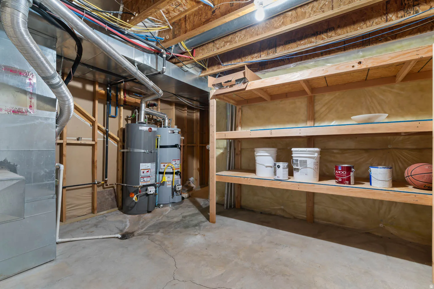 Concrete flooring throughout the utility space, featuring exposed wood ceiling joists and visible ductwork