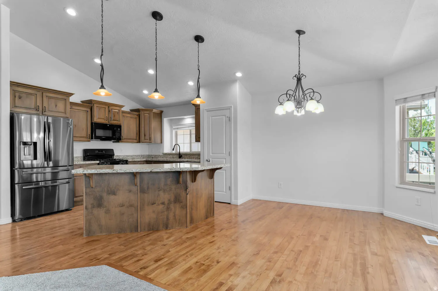 Open-concept dining/kitchen with hardwood floors, and granite countertops