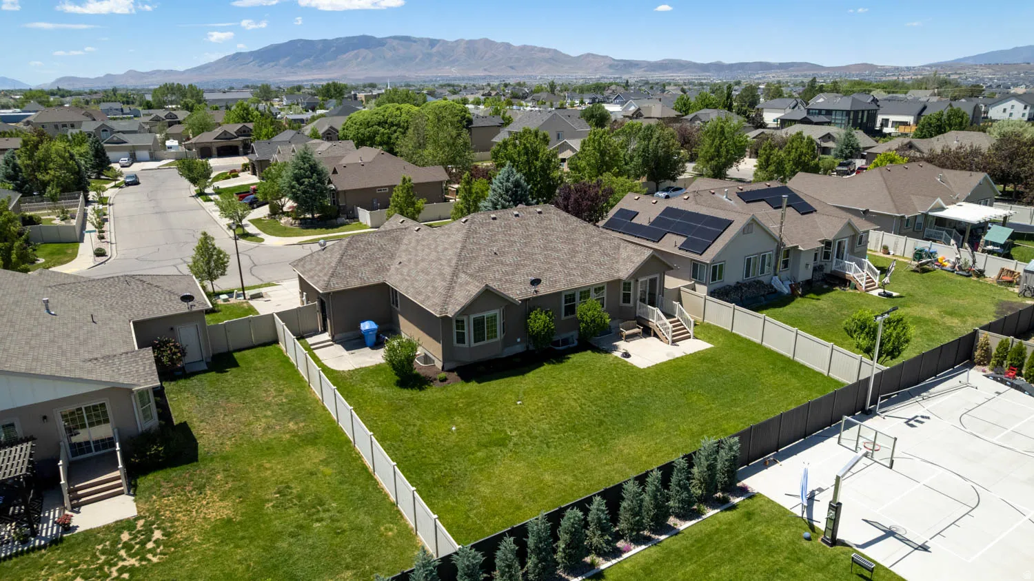 Expansive fenced backyard featuring a manicured lawn, an attached deck, and mature privacy trees