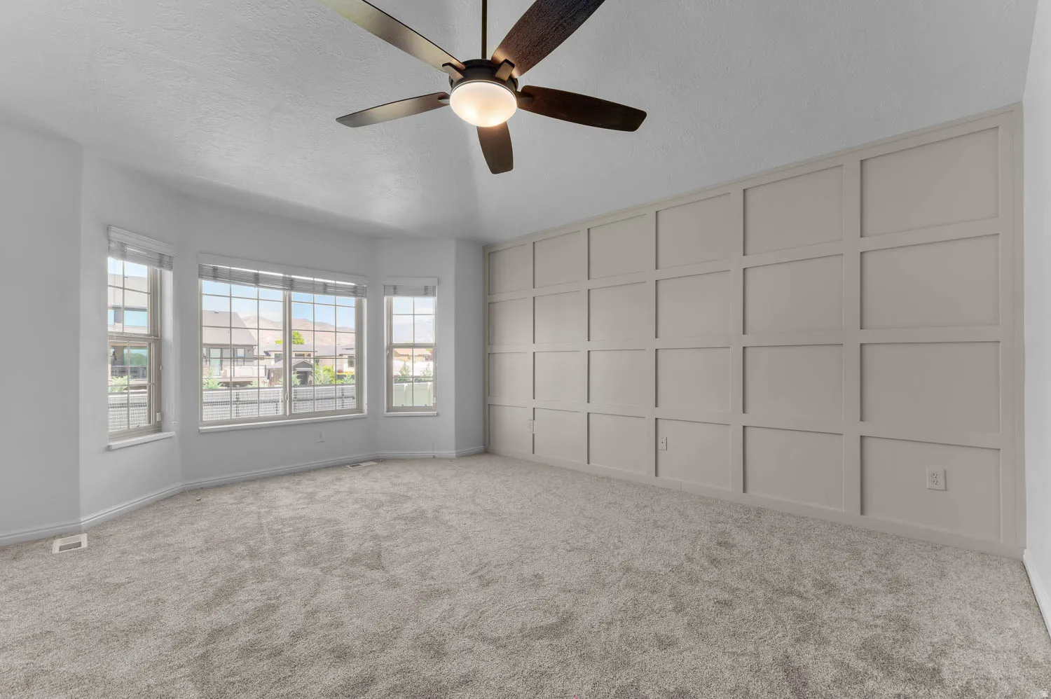 Neutral-toned carpeting complements a feature wall with decorative paneling. Primary Bedroom with walk-in closet and bath