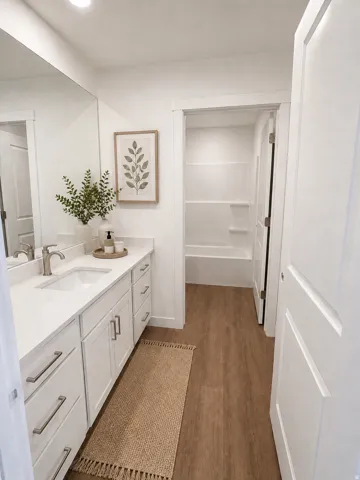 Bathroom featuring an expansive vanity with white cabinetry, a rectangular undermount sink, and a full-width mirror