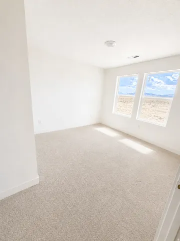 Bright room featuring a neutral carpet, white walls, and two large windows offering desert scenery