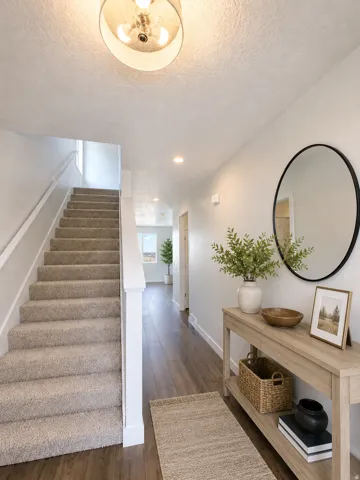 Entryway featuring wood-finish flooring, a carpeted staircase with white railings, and recessed ceiling lighting