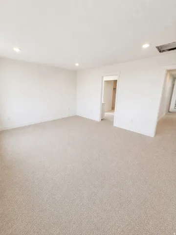 Spacious room featuring neutral carpeting and white painted walls